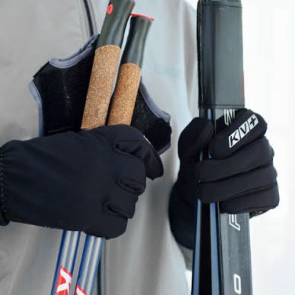 Close up of person wearing black gloves and a grey jacket, holding skis and poles.
