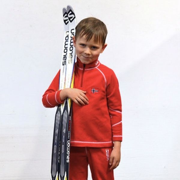 Boy wearing a red outfit and holding skis against a white background.