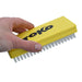 A hand holding a yellow TOKO brand cleaning brush with white bristles against a plain white background.