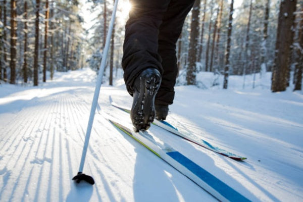 Person cross-country skiing on a snow-covered track with trees in the background